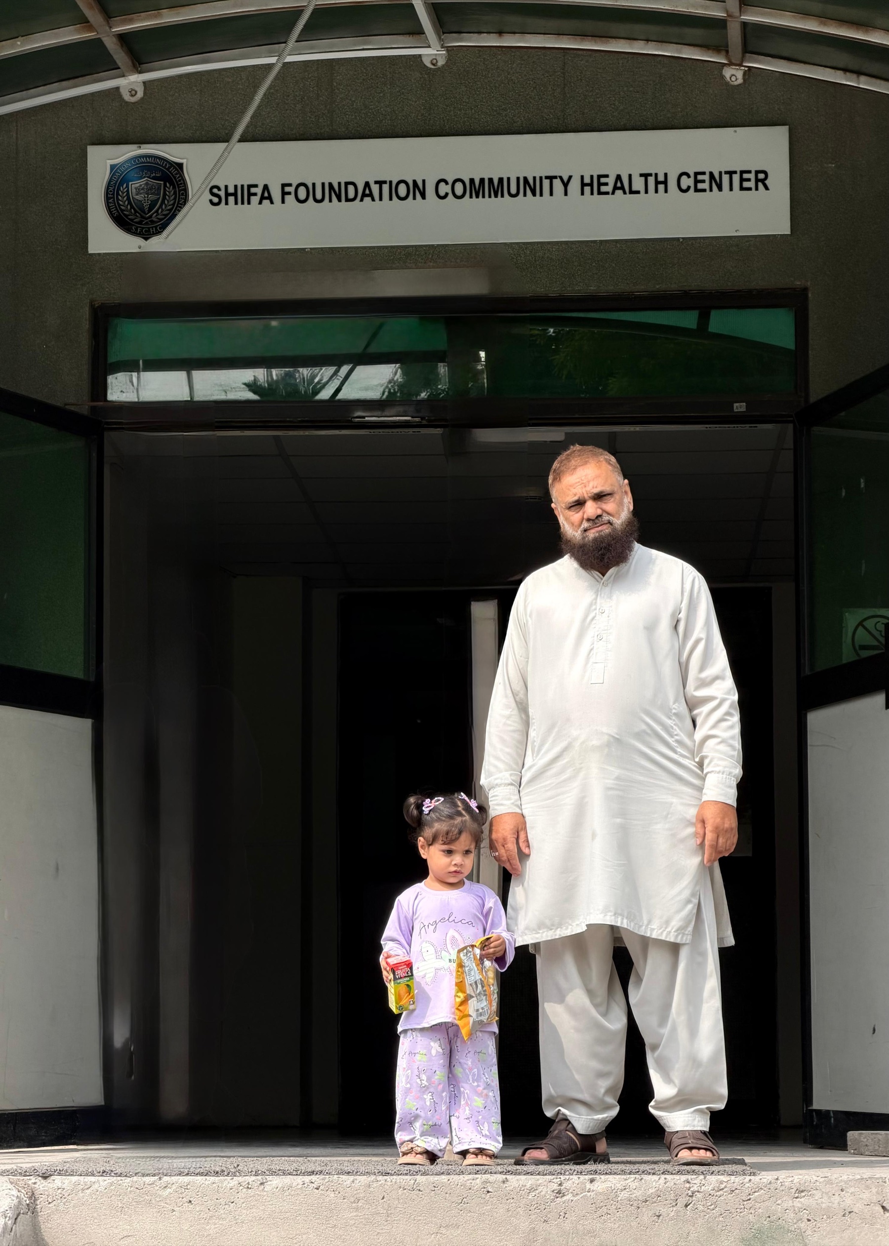 Mr. Ikramullah and his granddaughter outside the Shifa Foundation Community Health Center